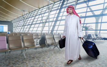 Portrait of Arabian businessman carrying a briefcase and luggage while walking in the airport terminal