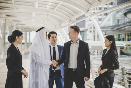 Portrait of business partners greeting one another by handshaking on the way to office.